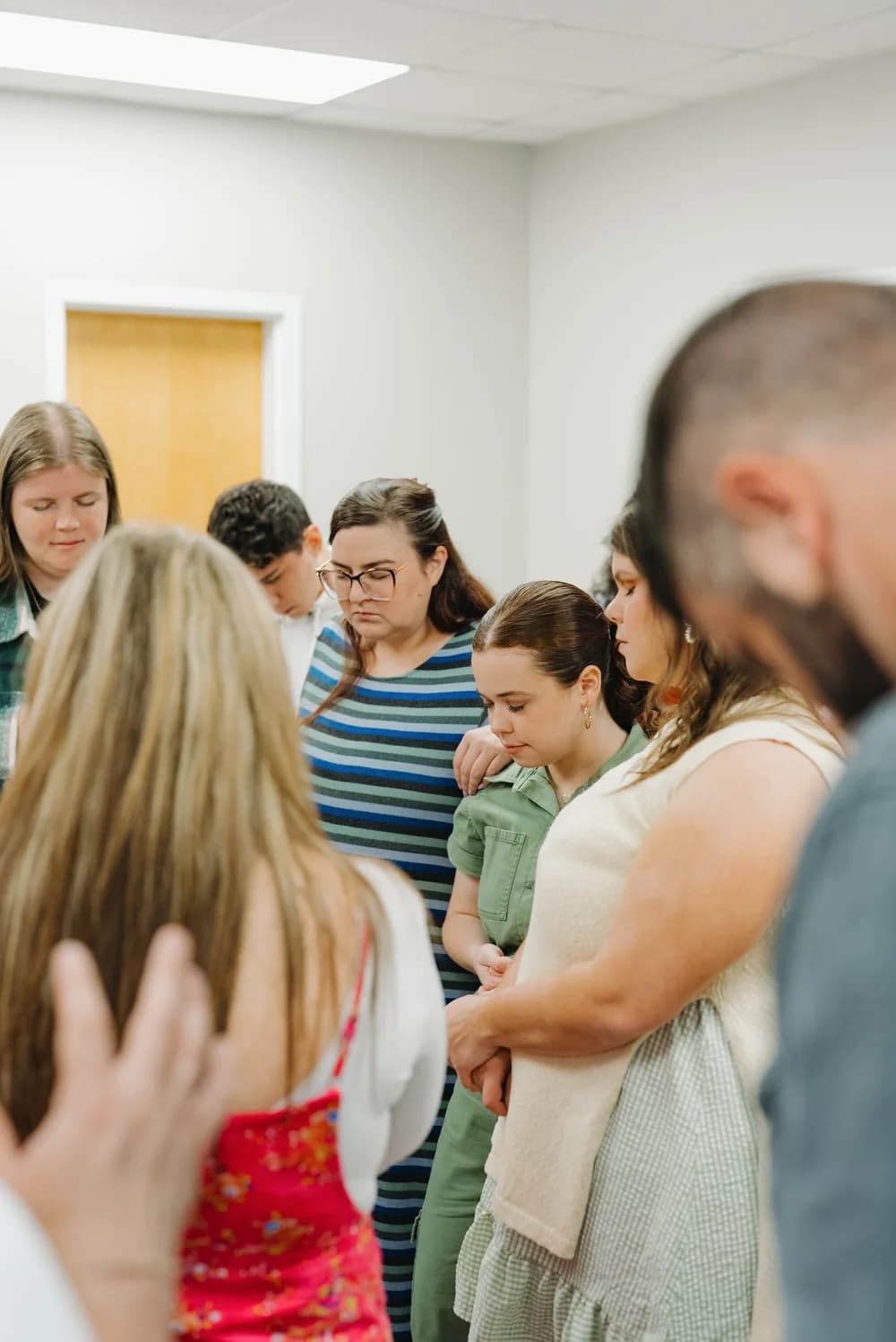 A group of people praying together with heads bowed