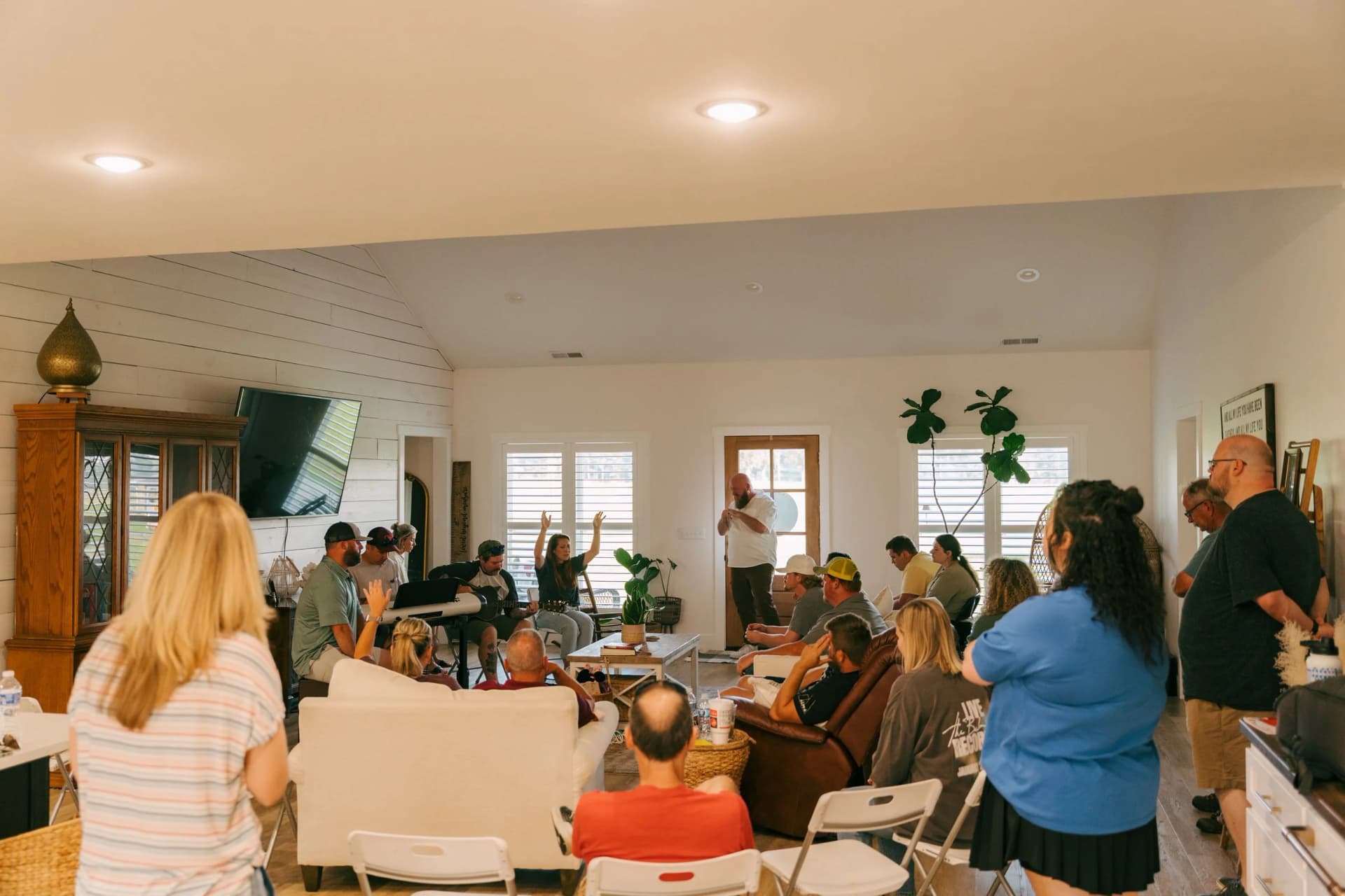 A Community Group worshiping together in a home, hands raised
