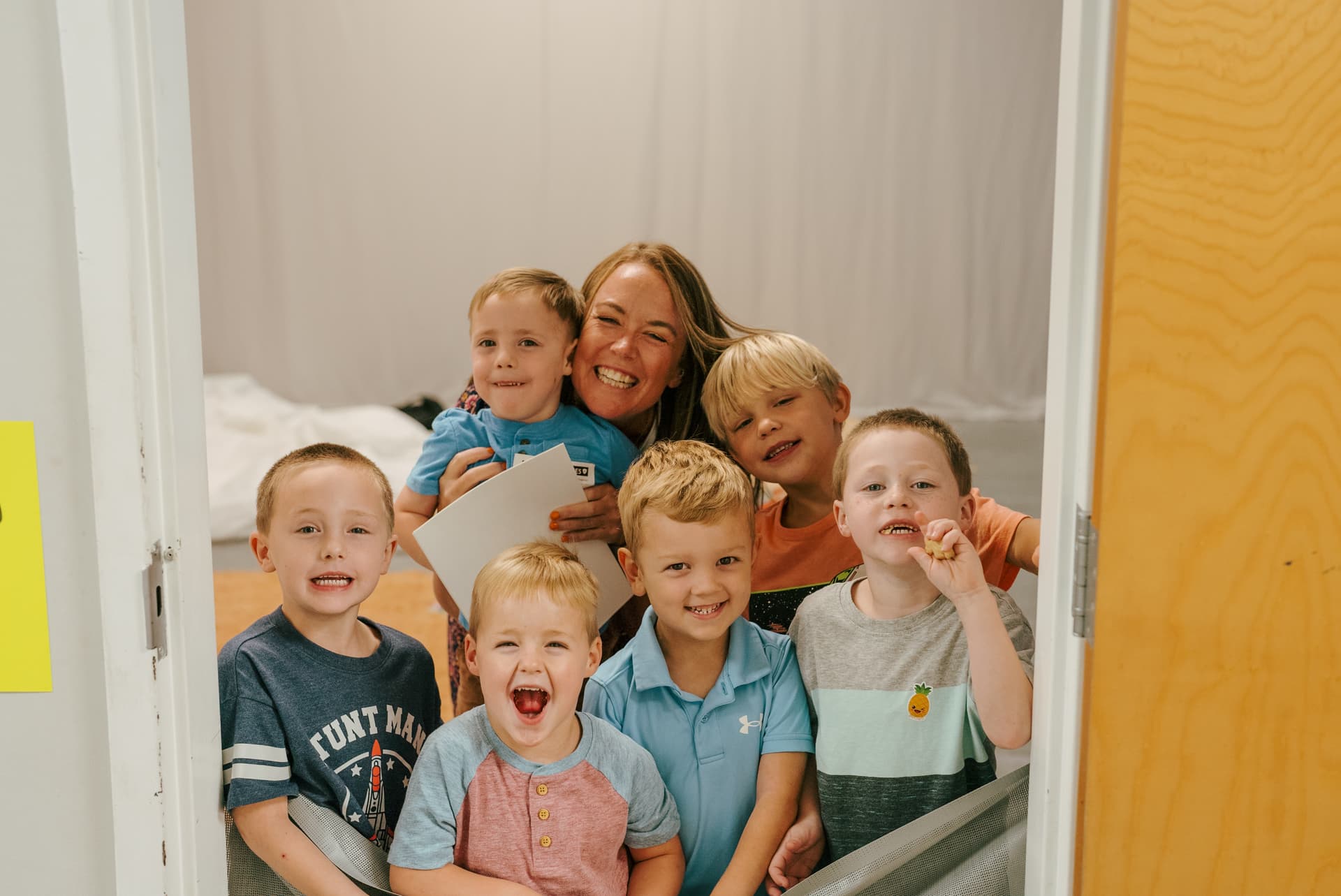 A Brighthouse Kids leader laughing with a group of happy children