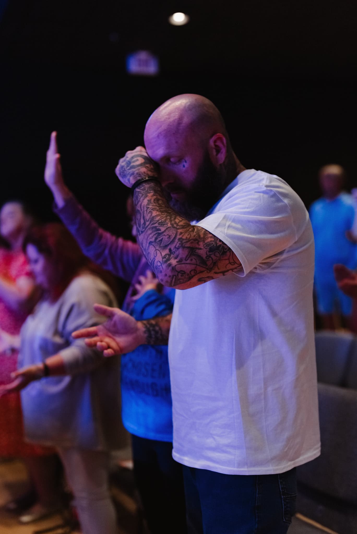 A man in worship with his head bowed during a Brighthouse Church gathering