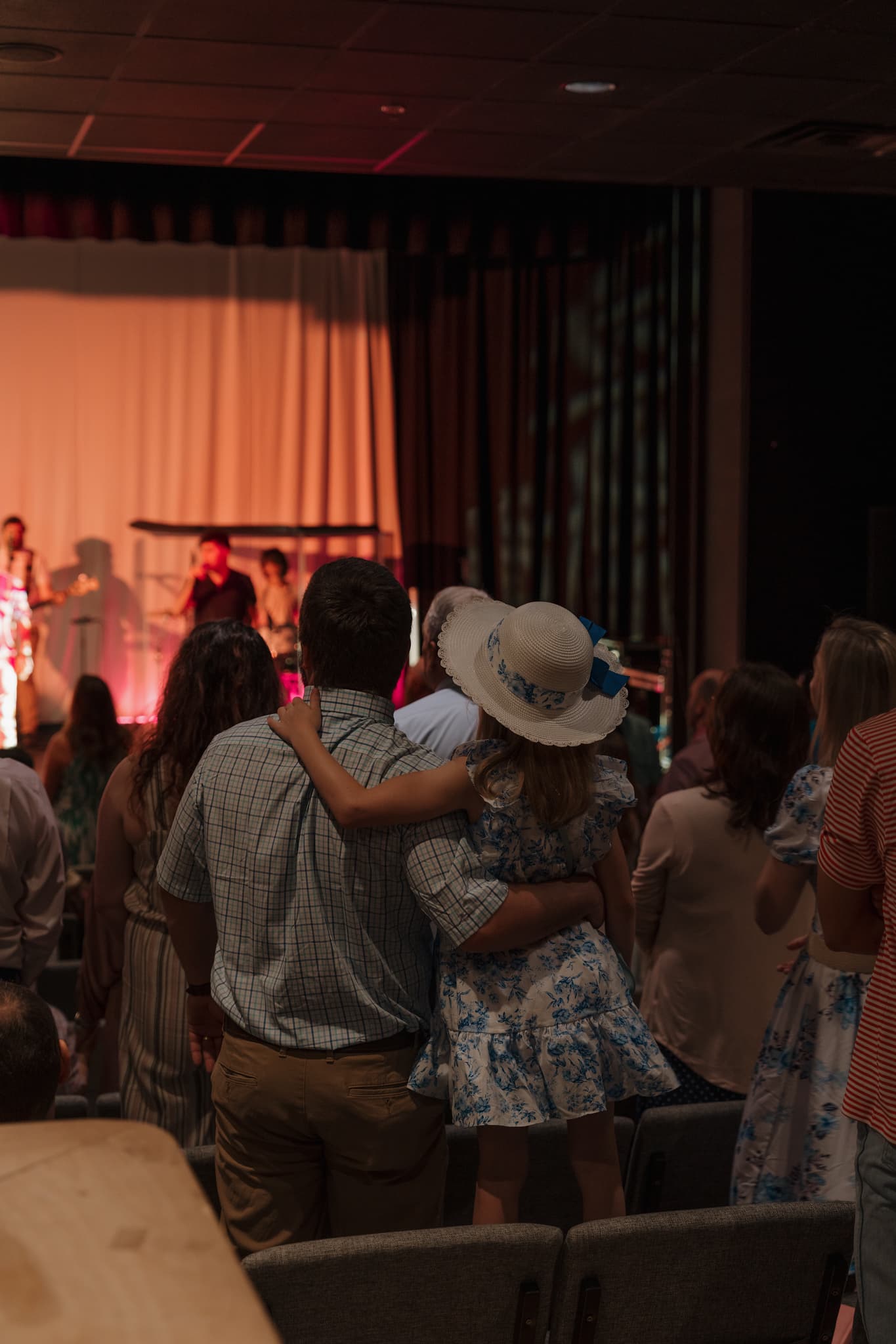 A father holding his young daughter during worship at a Brighthouse Church gathering