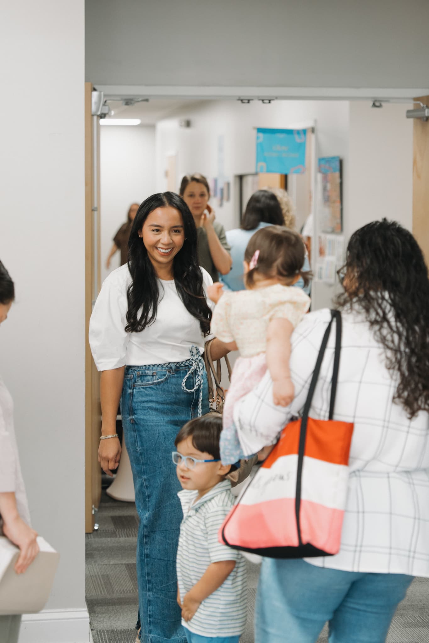 A volunteer warmly welcoming a family with young kids in the Brighthouse hallway